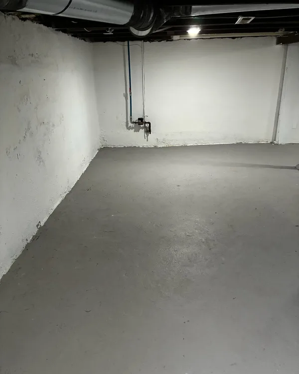 Empty basement with a painted grey floor and white walls