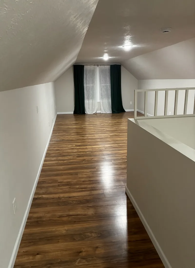Upstairs loft hallway with a wood-look floor and a sloped ceiling