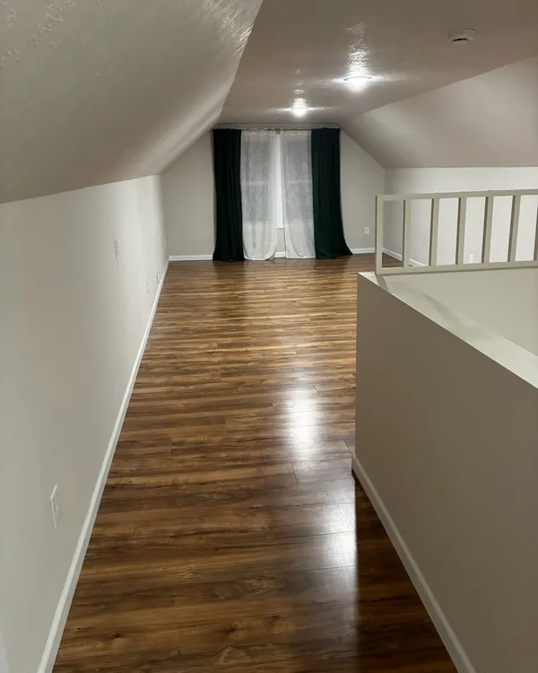 Upstairs loft hallway with a wood-look floor and a sloped ceiling