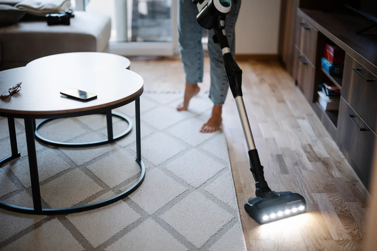 Vacuuming a patterned rug in a bright living room